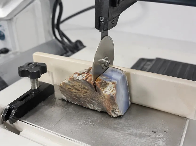 Thin electroplated diamond blade on trim saw sectioning rough gemstone material