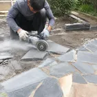 Landscaper cutting flagstone pavers for garden pathway installation