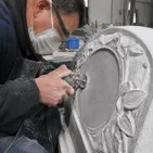 Stone carver using small-diameter diamond disc for detailed memorial headstone shaping
