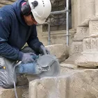 Mason carefully cutting aged limestone during heritage building restoration