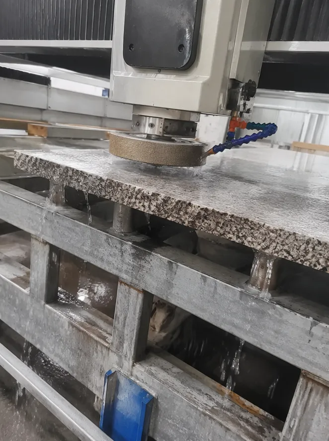 Diamond grinding wheel installed on a bridge saw calibration head processing granite slab