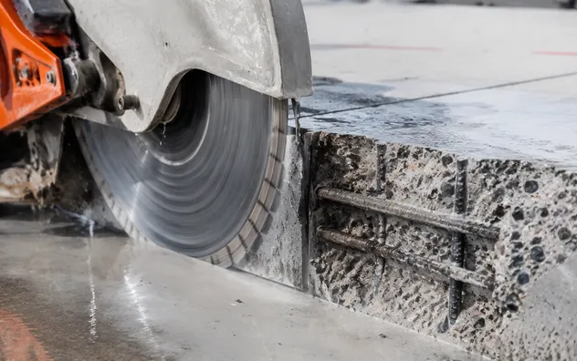 Diamond blade cutting through cured reinforced concrete with exposed rebar cross-section