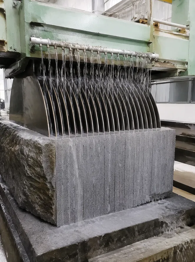 Multi-blade gang saw frame with parallel diamond blades cutting a stone block into slabs