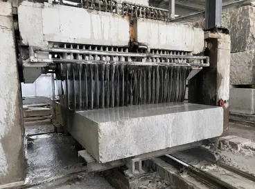 Multi-blade gang saw frame processing stone blocks in a quarry facility