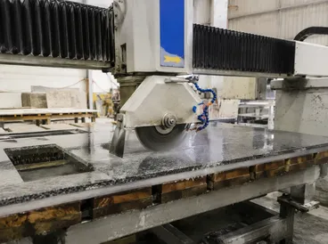 Bridge saw cutting granite countertop in a stone fabrication shop