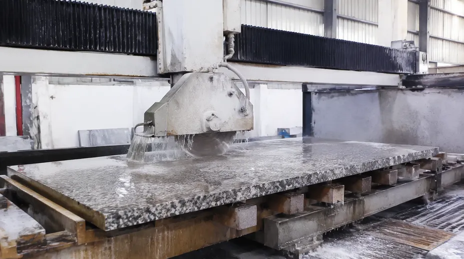 Bridge saw cutting granite slab in fabrication shop